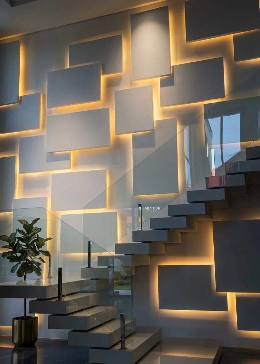 Offset square panels backlit in warm light rising beside a floating staircase